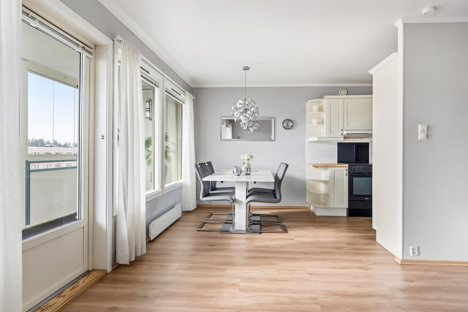 Pen kjøkkeninnredning med hvite fronter, laminat benkeplate og fliser på vegg. Galleribilde