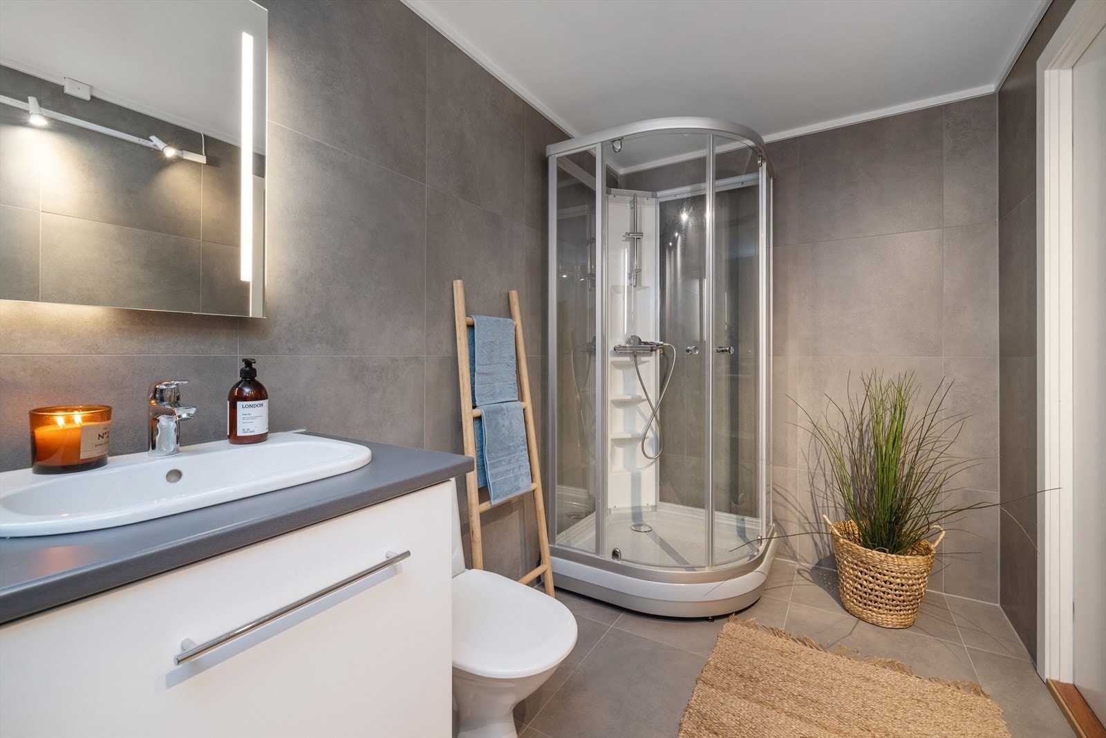 Badet er utstyrt med dusjkabinett, servantinnredning med LED-speil og opplegg for vaskemaskin. Galleribilde