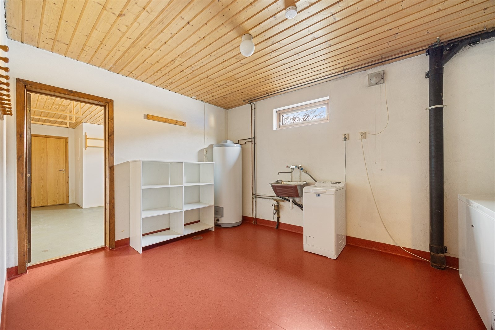 Romslig vaskerom innredet med skyllekar og opplegg for vaskemaskin. Rommet har belegg med varmekabler på gulv og malt puss på vegger. Det er elektrisk styrt vifte på vegg. Galleribilde