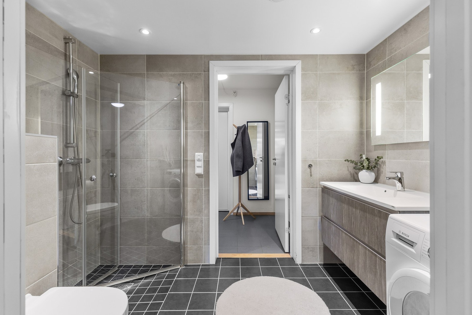 Badet har vegghengt toalett, dusjnisje, stor baderomsinnredning og opplegg for vaskemaskin. Galleribilde