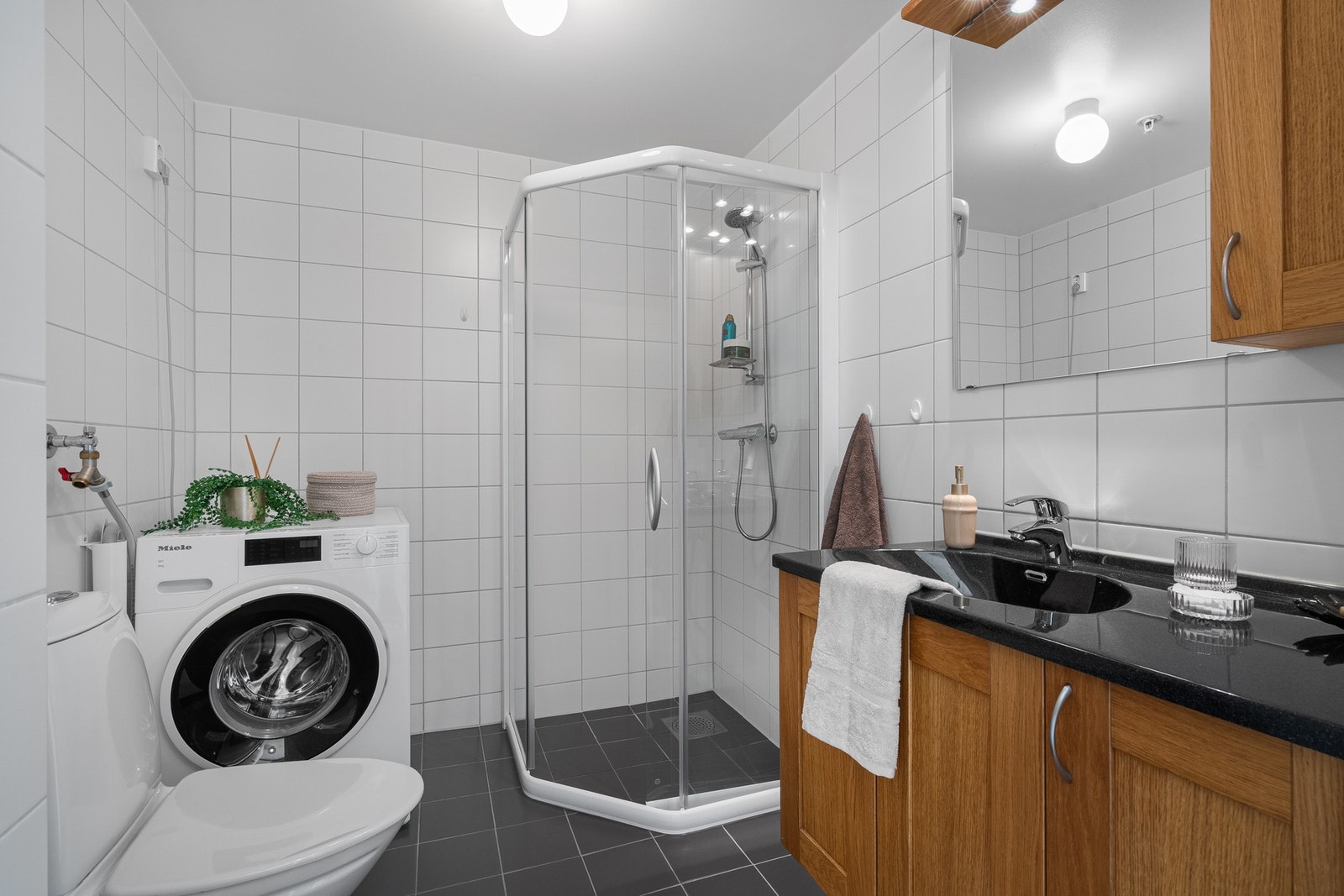 Flislagt bad med moderne uttrykk og opplegg for vaskemaskin. Galleribilde