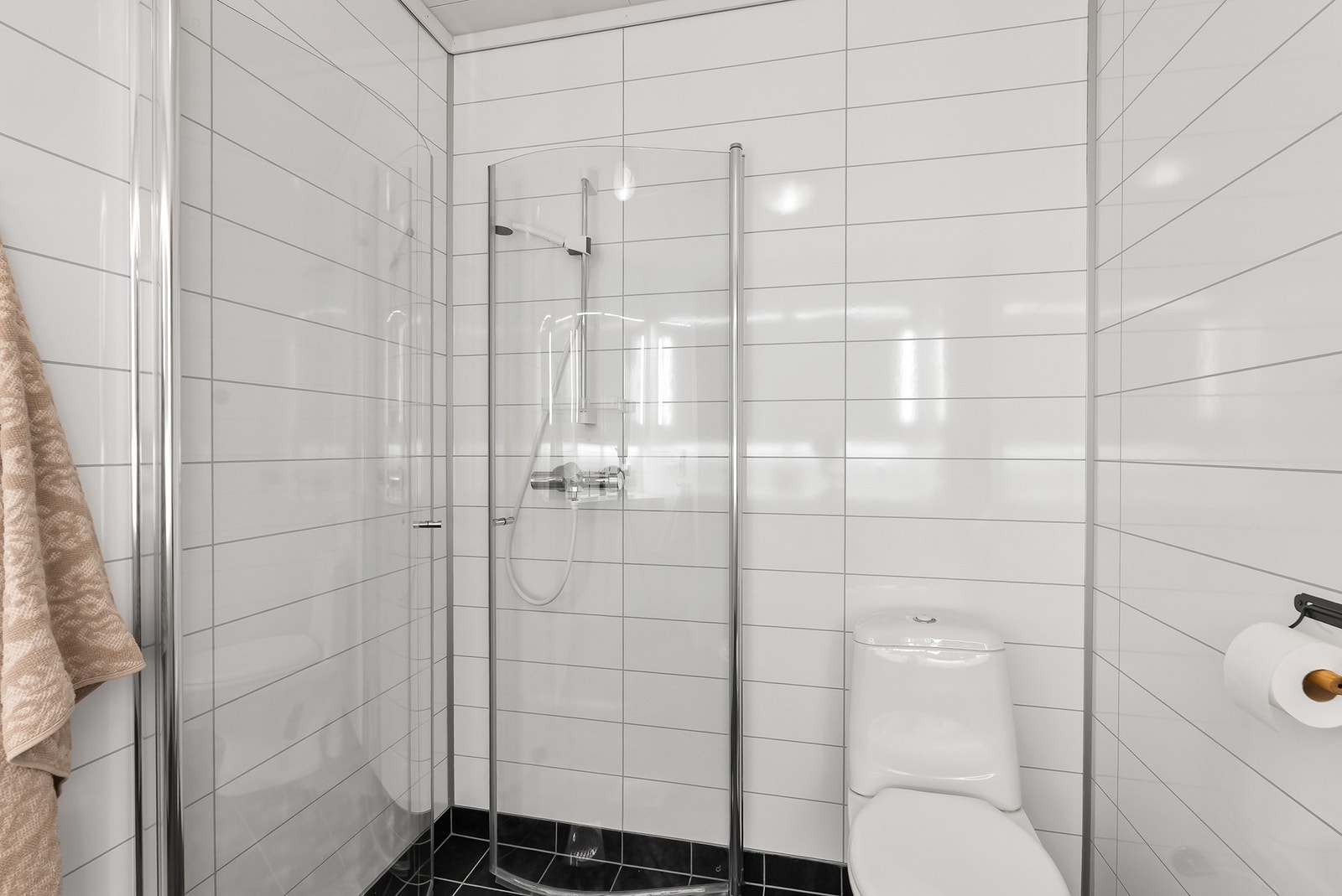 Dusjhjørne med innfellbare vegger og garnityr på vegg. Gulvstående toalett. Galleribilde