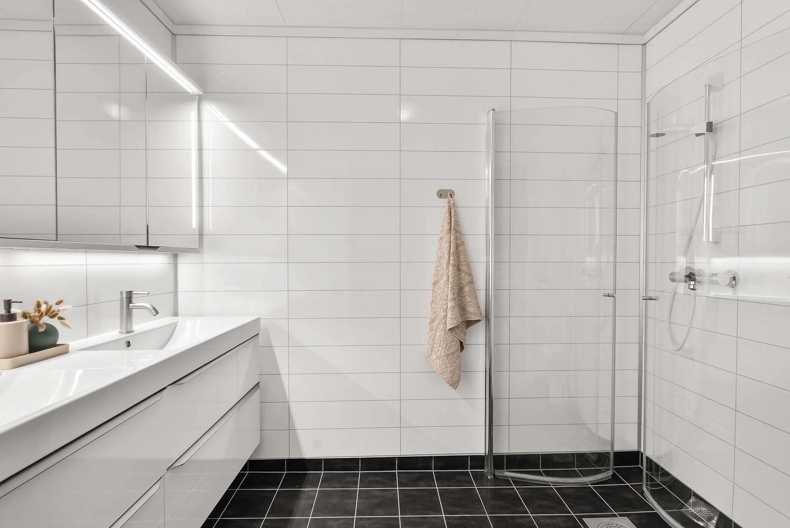 Pent og tidløst bad i 1. etg med flislagt gulv og våtromsplater på vegg. Varmekabler i gulv. Galleribilde