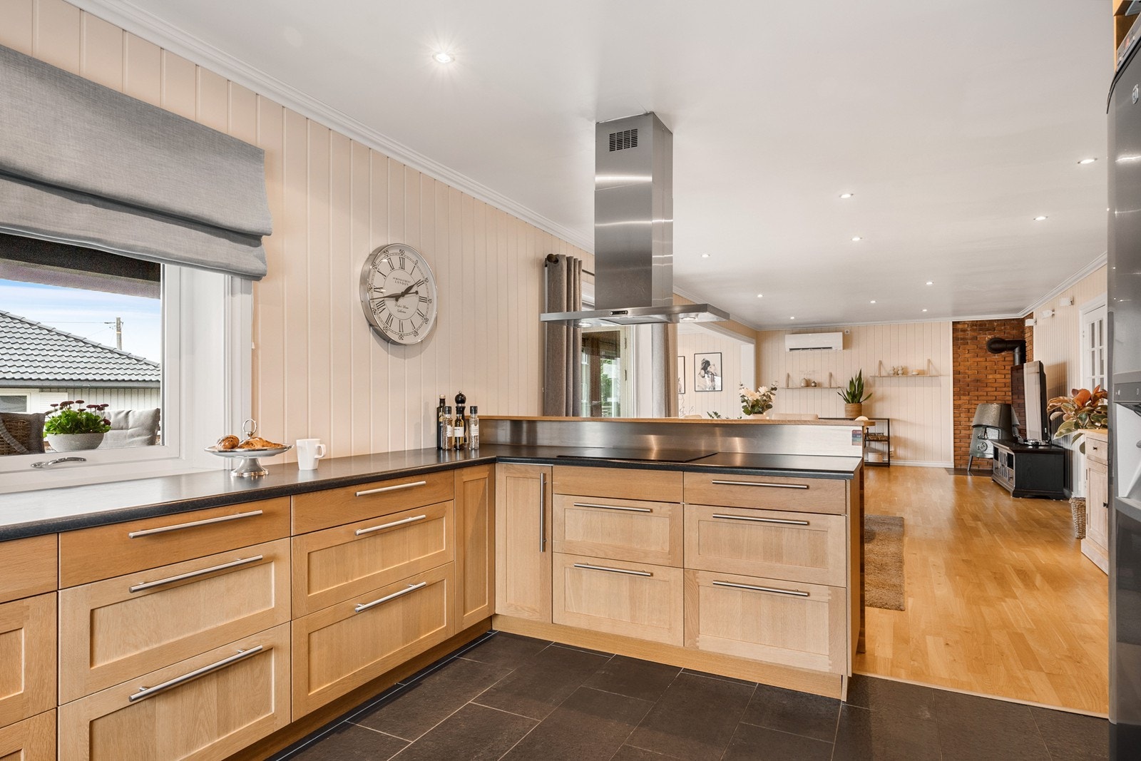 En kjøkkenhalvøy og overgangen fra parkett til flis med varmekabler gir et naturlig skille mellom stue og kjøkken. Galleribilde