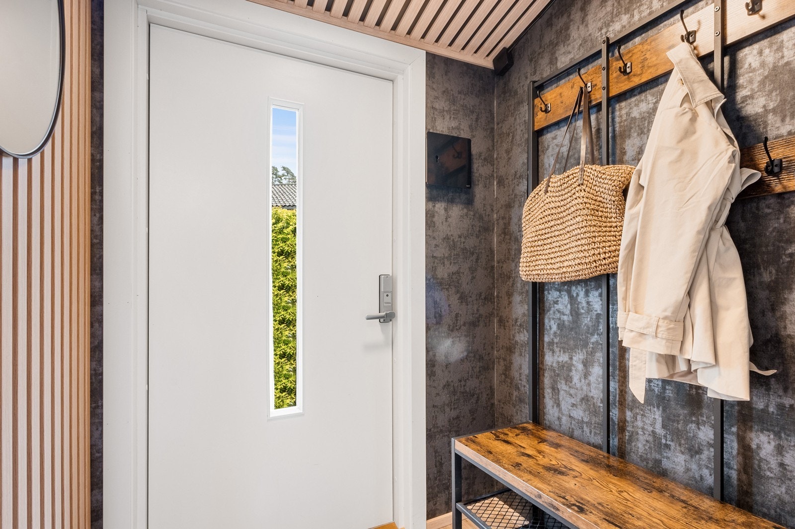 Entreen ønsker velkommen med dekorative spiler i tak og delvis på vegg, knagger, sittebenk og skostativ. Galleribilde