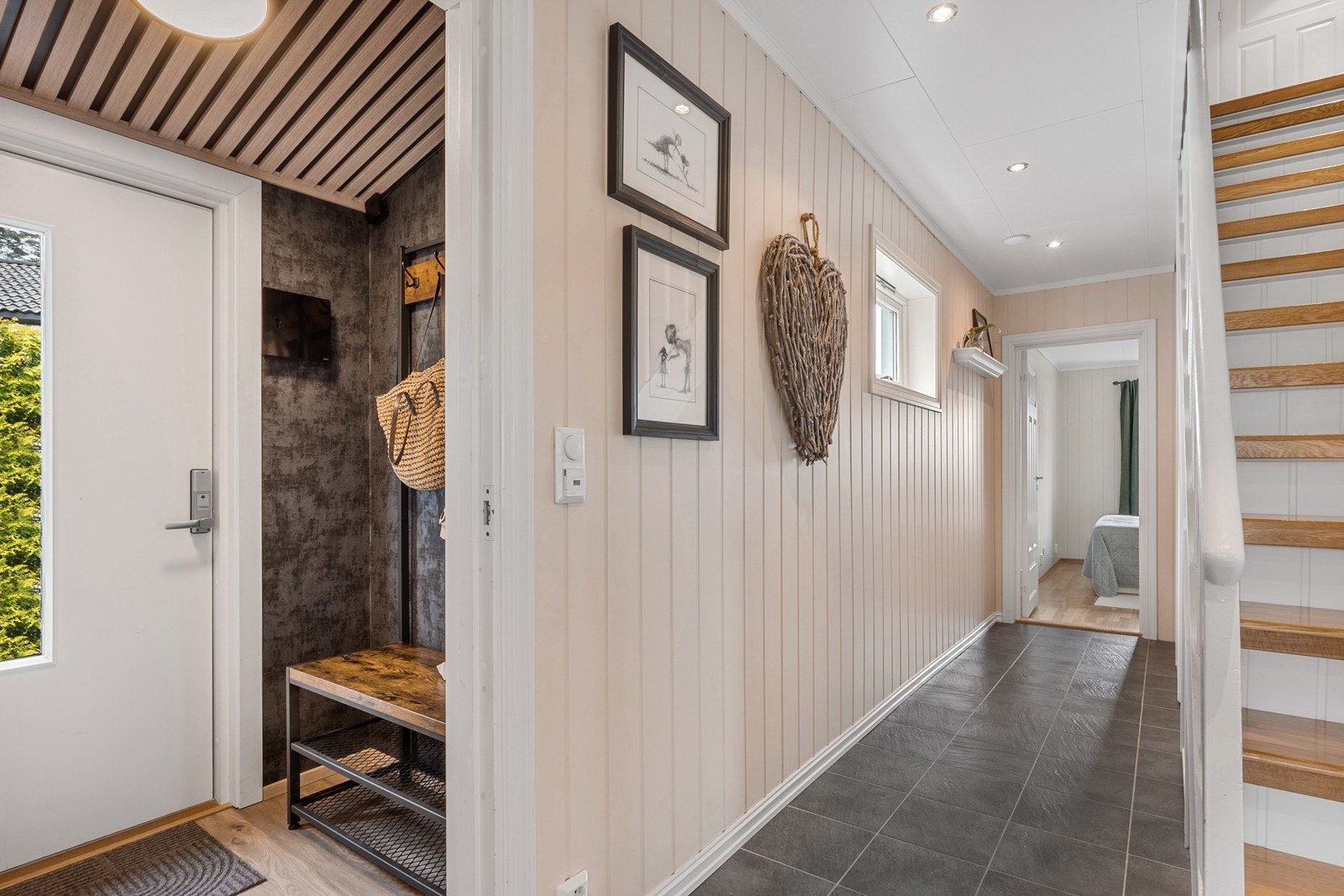 Flislagt gang med gulvvarme fører videre til etasjens bad, et soverom, stue og trapp til 2. etasje og kjeller. Galleribilde