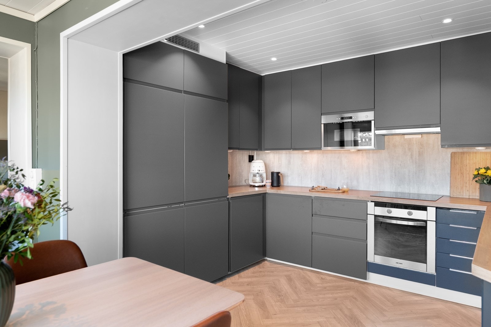 Ikea kjøkkeninnredning fra år 2022 med slette mørke fronter, benkeplater av laminat og vask av kompositt samt plater på vegg over benk. Galleribilde