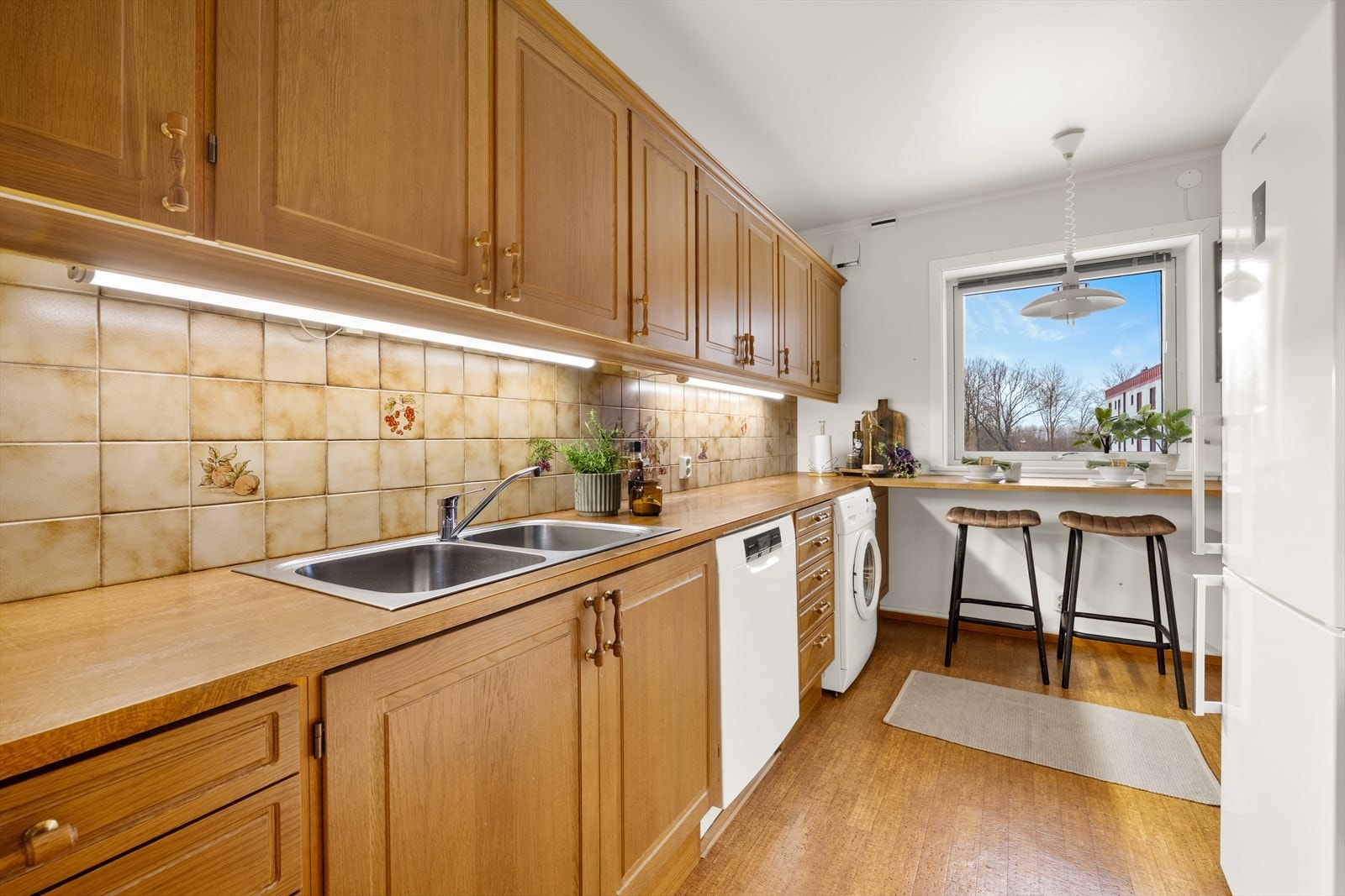 Kjøkkenet har innredning med profilerte fronter. Benkeplaten er av laminat. Det montert oppvaskmaskin og vaskemaskin på kjøkken. Godt med skapplass, fliser over benk. Galleribilde