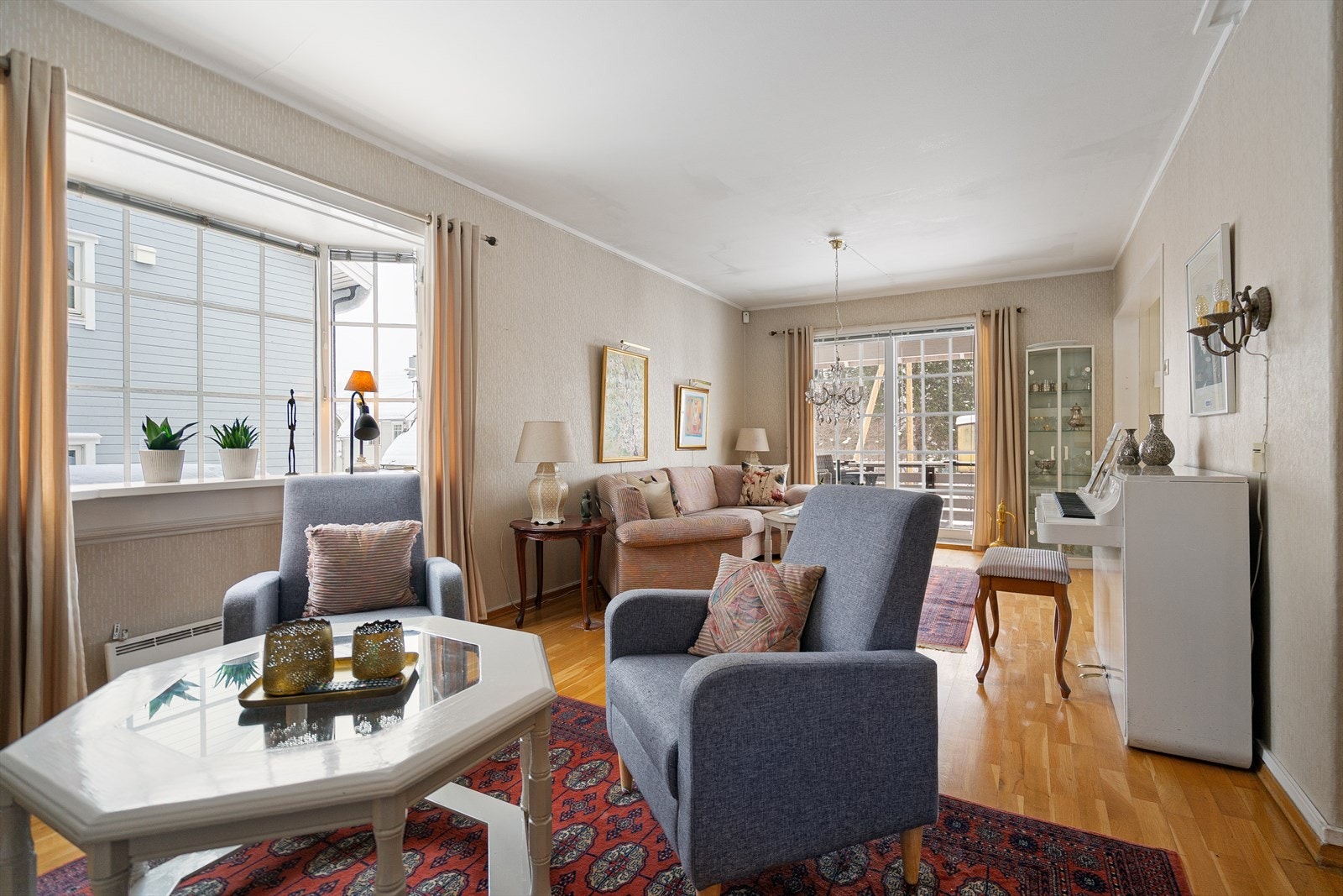 Stue med flere møbelsoner og store vindusflater som slipper inn godt med naturlig lys Galleribilde