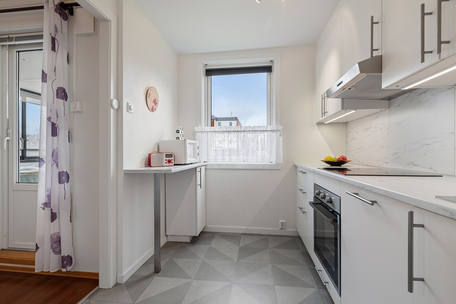 Fliser på veggen under overskapene og en stålkum med ettgreps blandebatteri kompletterer innredningen. Galleribilde