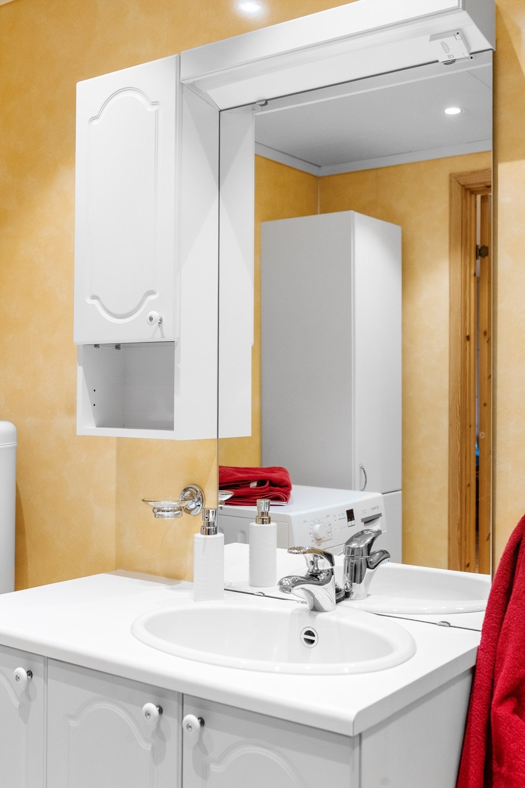 Badet inneholder servant med underskap, overskap, lys, speil og veggmontert høyskap. Galleribilde