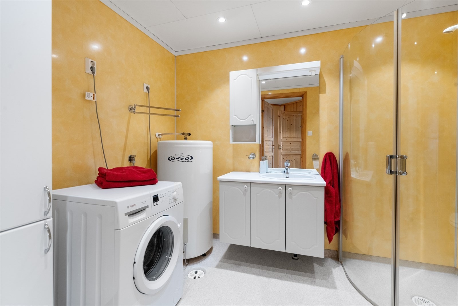 Videre inneholder badet gulvmontert toalett, dusjhjørne, opplegg til vaskemaskin og varmtvannstank på ca. 200 liter. Galleribilde