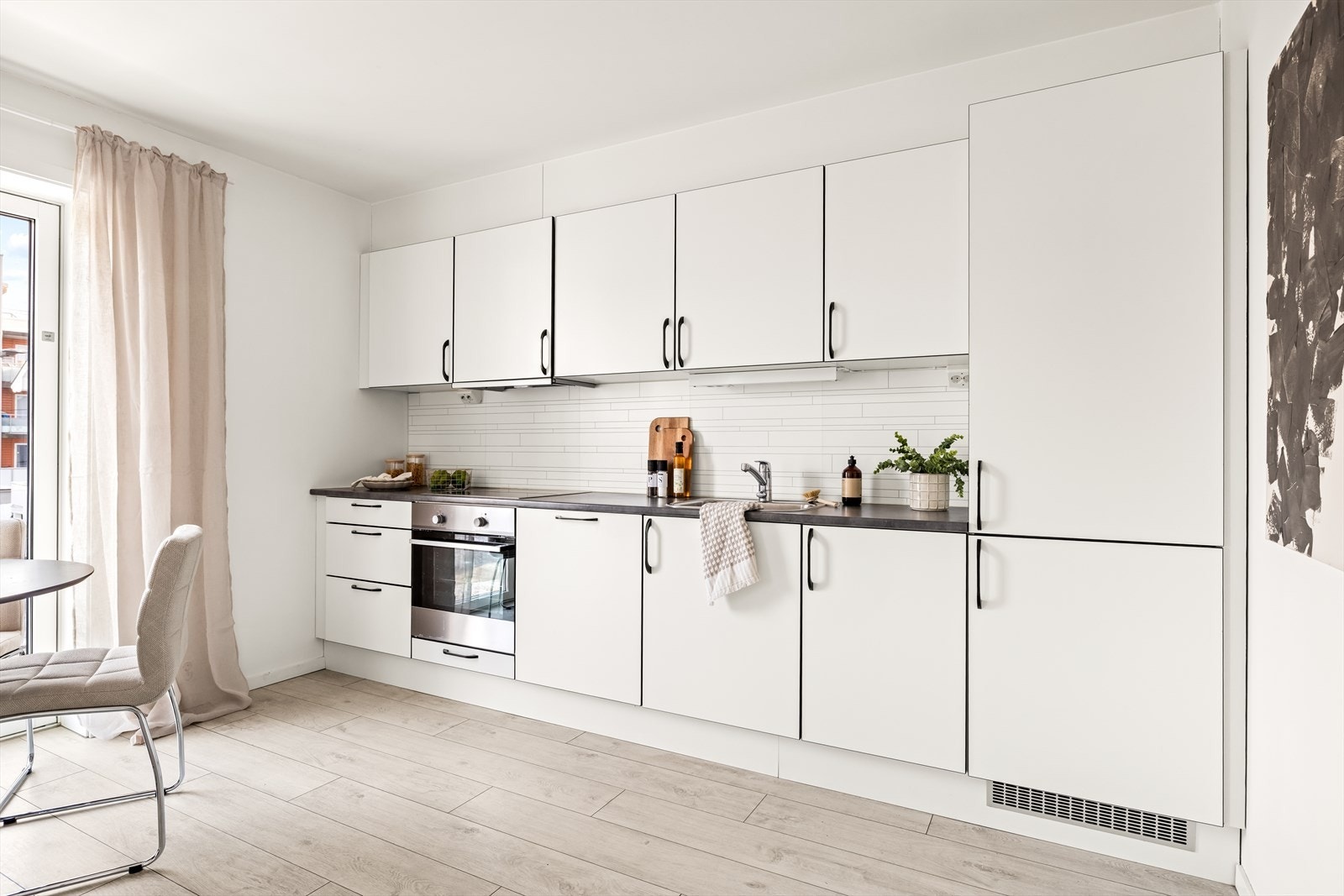 Leiligheten har et funksjonelt og lekkert kjøkken med integrerte hvitevarer og hvite, glatte fronter. Galleribilde