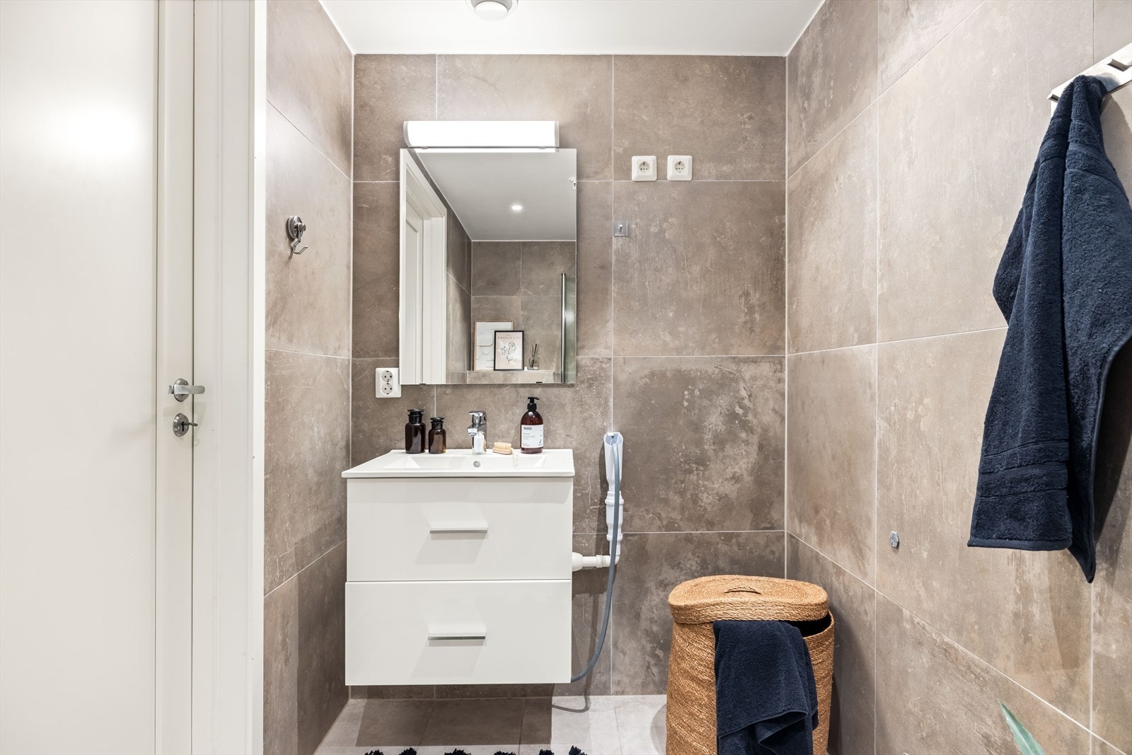 Badet er innredet med hvit servant med underskap, speil og opplegg for vaskemaskin. Galleribilde