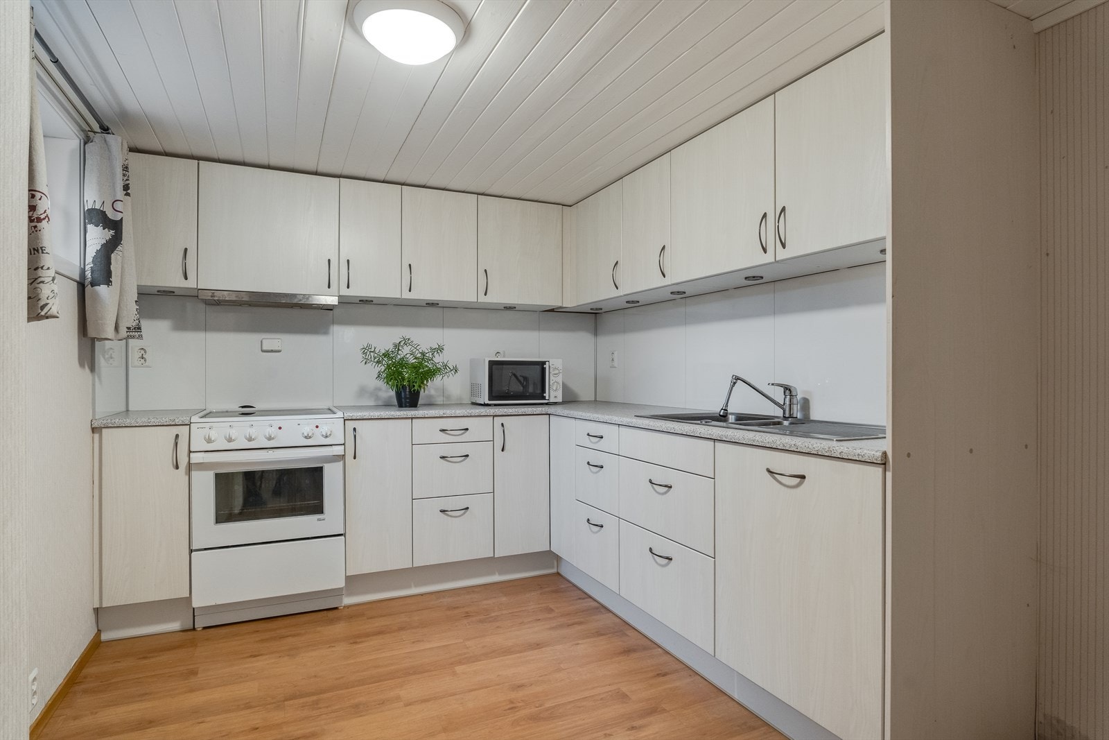 Kjøkken med rikelig skap- og skuffeplass samt benkeplass, med integrert oppvaskmaskin og frittstående komfyr. Galleribilde