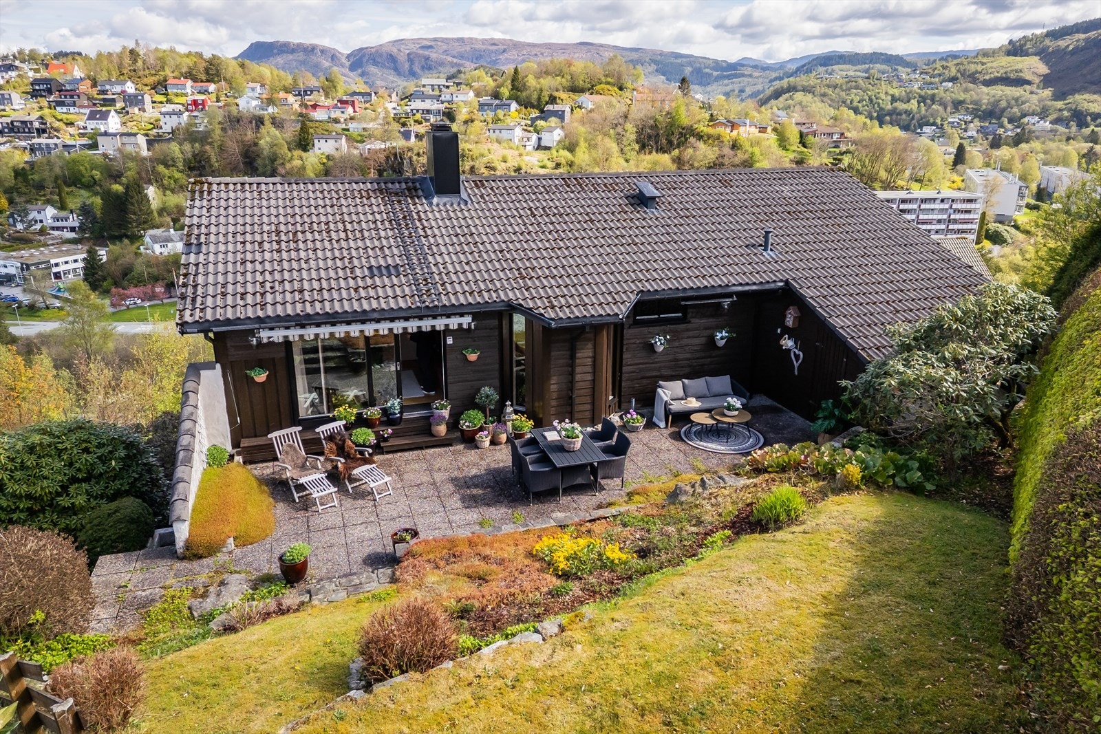 Ute venter en frodig og pent opparbeidet hage med lune kroker, solrike terrasser og god plass til både hverdag og helg. Galleribilde