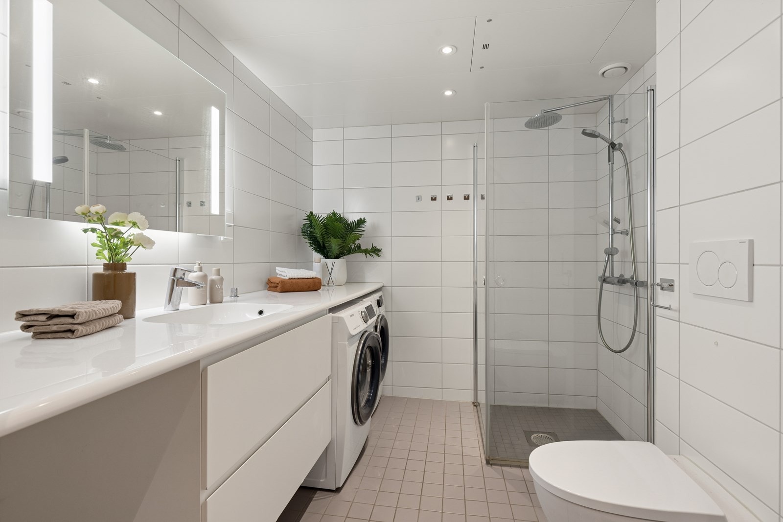 Badet er innredet med dusjhjørne med innfellbare glassdører og vegghengt toalett med innebygd sisterne. I tillegg er det opplegg for vaskemaskin og gulvvarme for ekstra komfort. Galleribilde