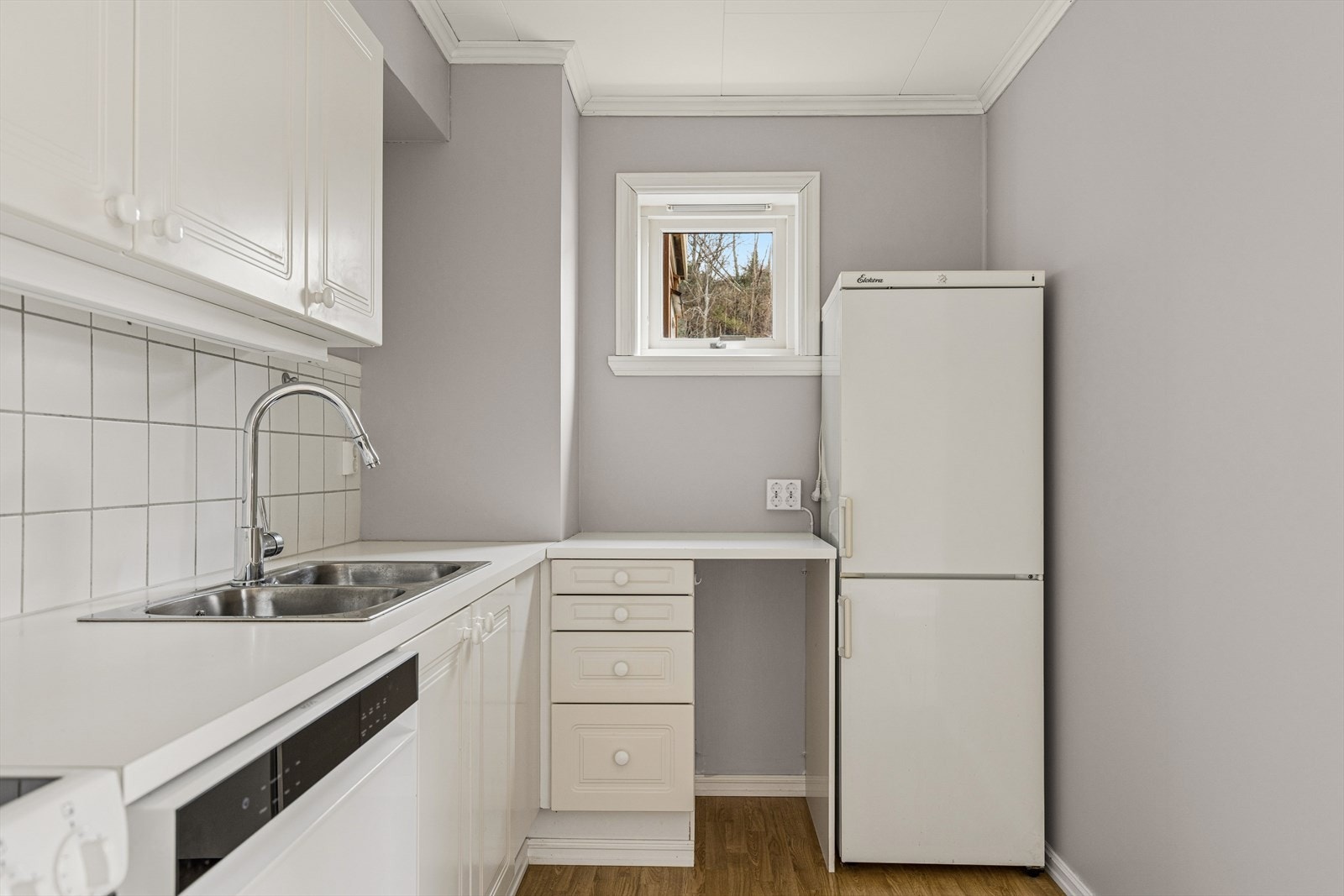 Innredningen består av profilerte fronter, laminert benkeplate og fliser over benk. Kjøkkenet er utrustet med kjøl/fryseskap, oppvaskmaskin, komfyr og kjøkkenventilator med avtrekk ut. Galleribilde