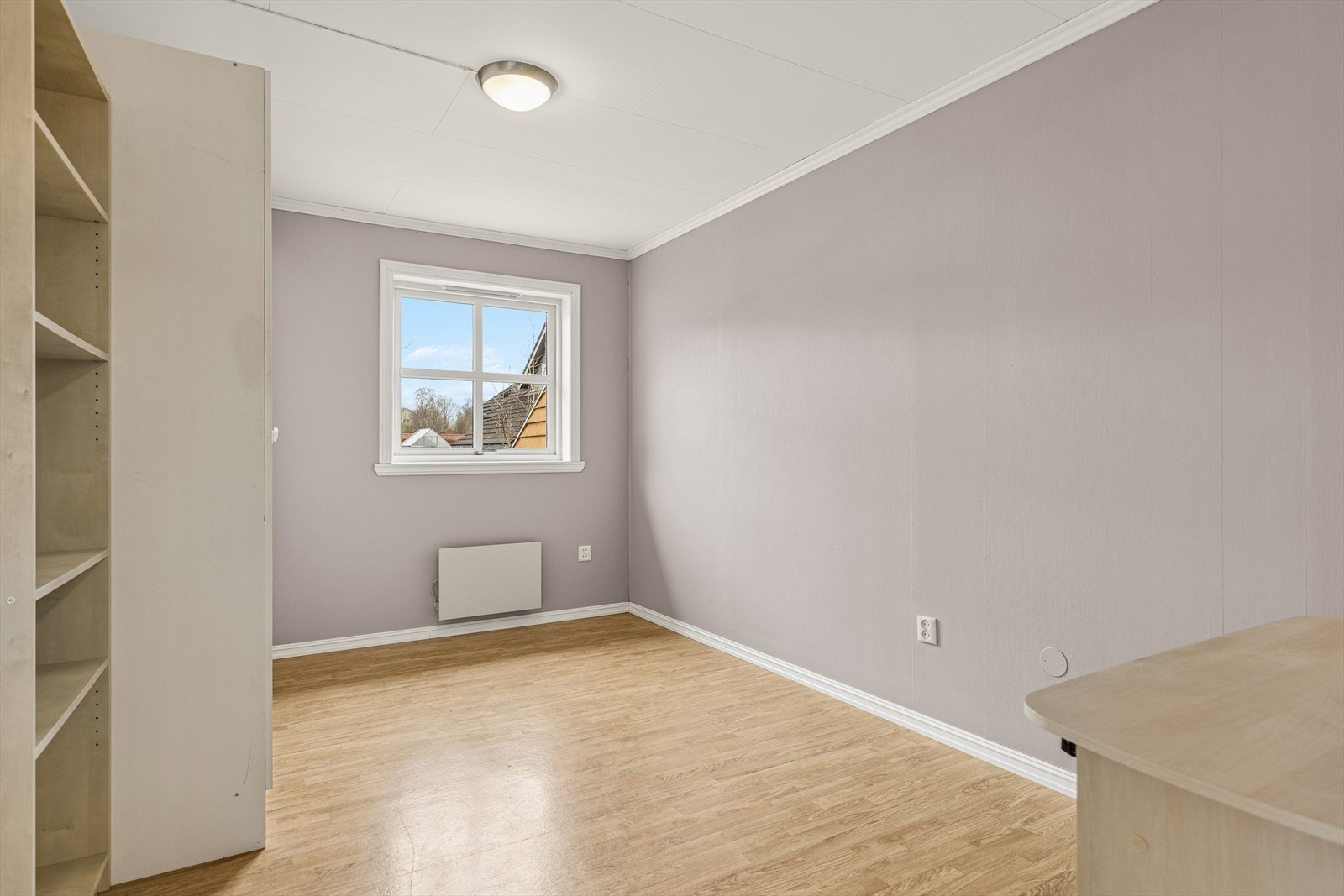 Rommet har gulvbelegg og malte plater/tapet på veggene, og et vindu som vender ut mot rolige omgivelser. Galleribilde