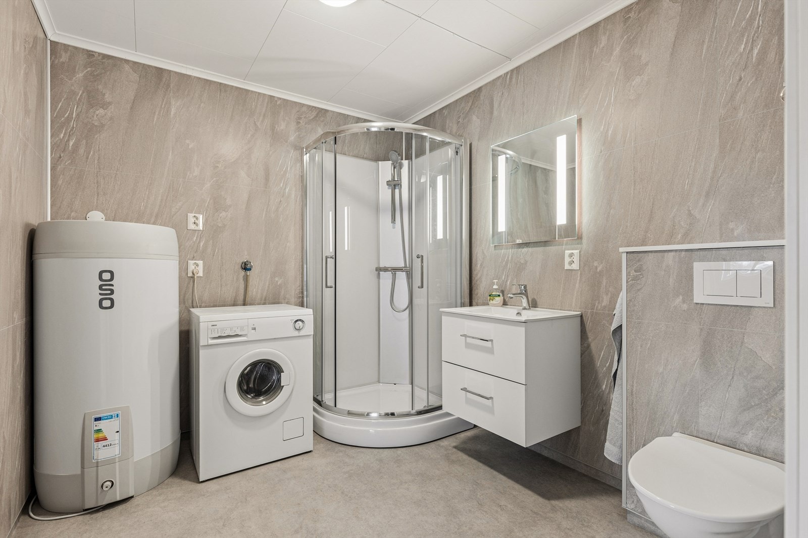 Badet er kombinert vaskerom med opplegg for vaskemaskin. Varmtvannstanken på ca. 200 liter er ny fra 2026. Galleribilde
