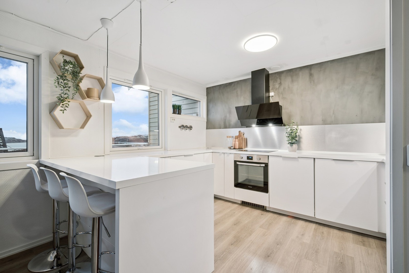 Stilrent kjøkken fra 2017 med lyse flater og kjøkkenøy med sitteplass - perfekt for både matlaging og hverdagsprat Galleribilde