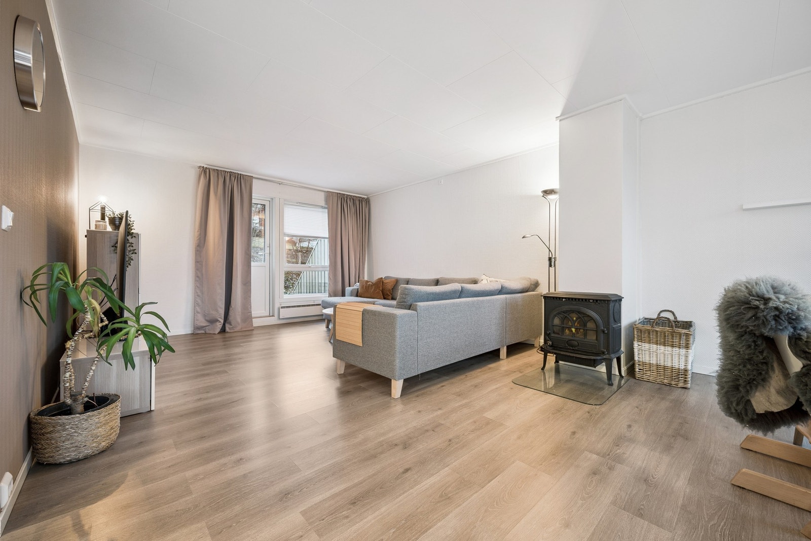 Lys stue med kontrastvegg i jordfarge og vedovn Galleribilde