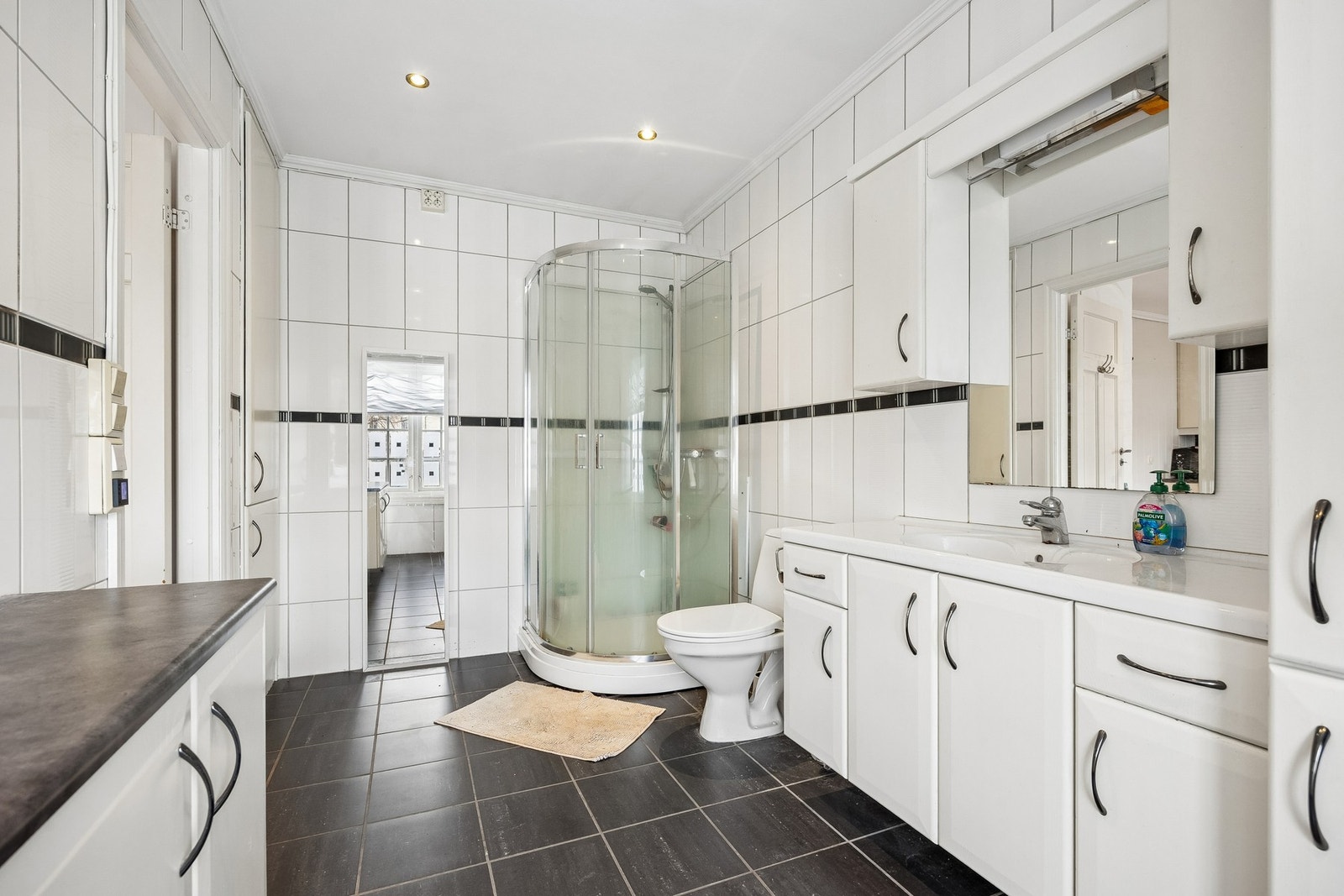 Badet har flis på gulv og vegger og er utstyrt med gulvvarme, servantsskap, wc, dusjkabinett og opplegg for vaskemaskin. Galleribilde