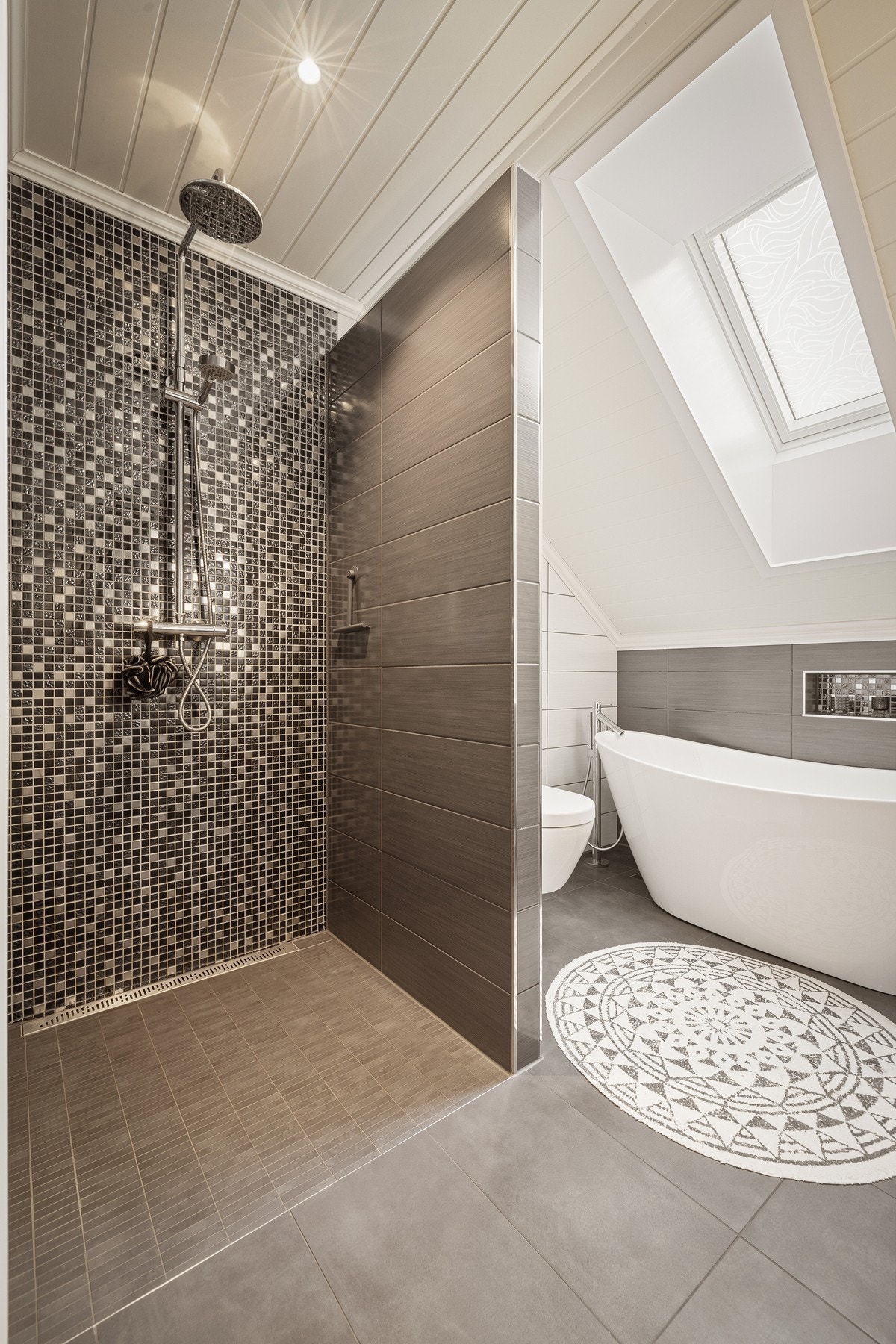 Rommet har innredning med nedfelt servant, veggmontert toalett, badekar og dusjvegger/hjørne Galleribilde