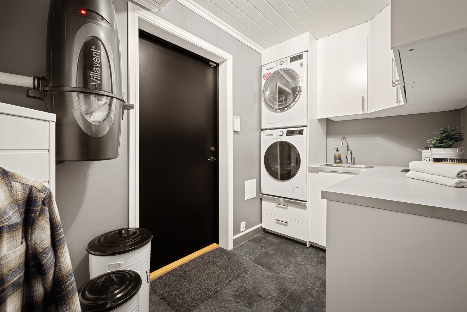 Rommet har innredning med nedfelt vask og benkeplate av laminat, varmtvannstank, vaskemaskin, vannskap, elskap, vannbårenvarmeskap og motorenhet for balansert ventilasjon. Galleribilde