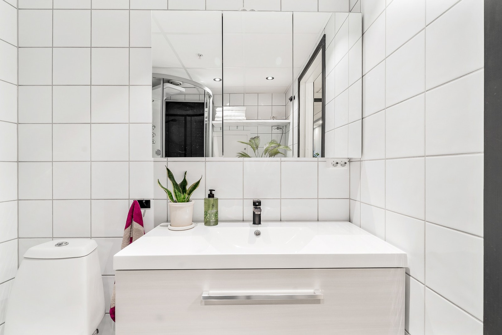 Moderne baderomsinnredning, speilskap, toalett, dusjkabinett og opplegg for vaskemaskin på badet. Galleribilde