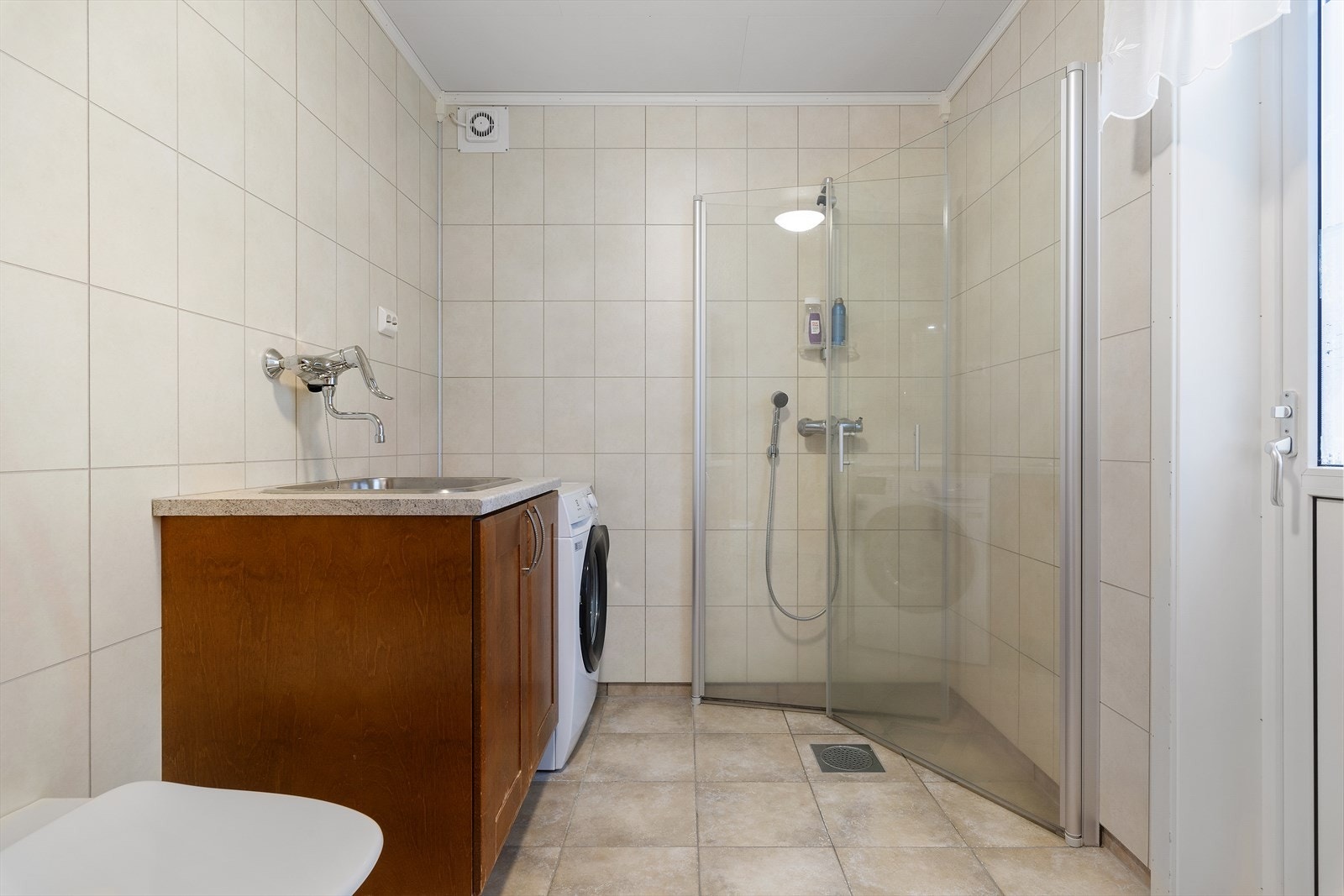 Her er det vegghengt toalett, opplegg for vaskemaskin, utslagsvask og dusjhjørne med innfellbare dører. Galleribilde