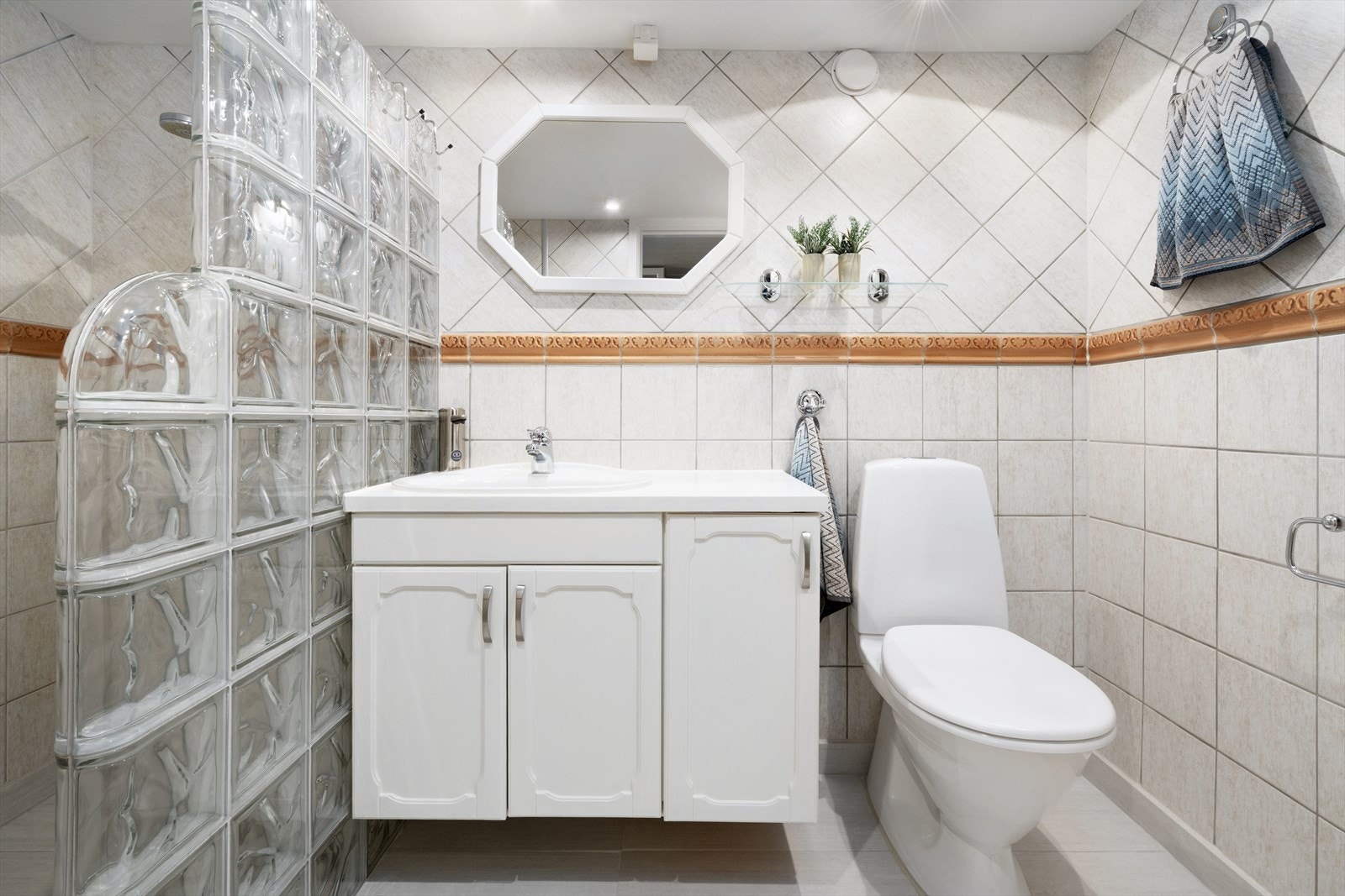 Badet i kjeller er innredet med innredning med nedfelt servant, toalett og dusjvegger/hjørne i glassbyggerstein. Galleribilde