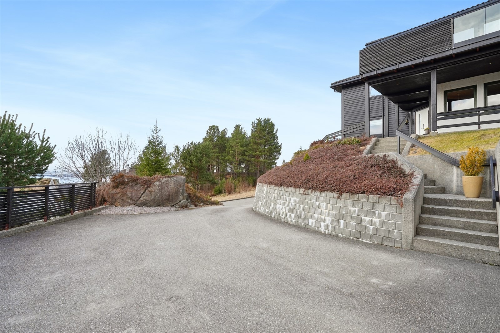 Fra den asfalterte gårdsplassen fører en støpt trapp opp til boligens inngangsparti. Galleribilde