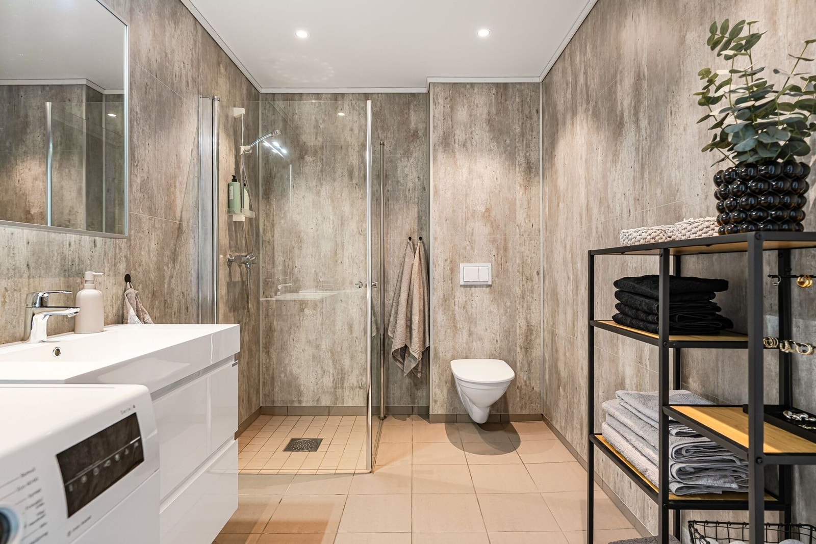 Badet er utstyrt med baderomsinnredning, dusjhjørne, toalett og opplegg for vaskemaskin Galleribilde