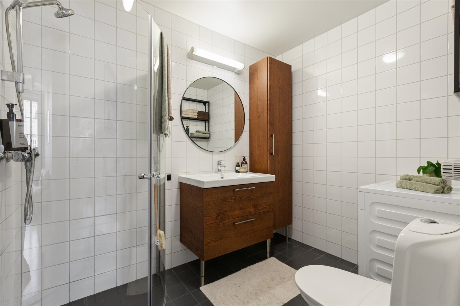 Baderommet er flislagt med gulvvarme og har montert dusj, nedfelt servant med underskap, vaskemaskin og WC Galleribilde