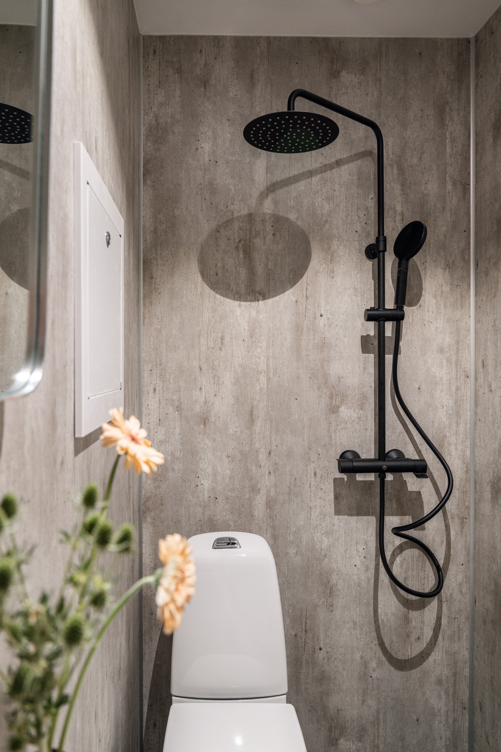 Baderommet har mørke fliser på gulv med elektriske varmekabler og baderomsplater på veggene. Galleribilde