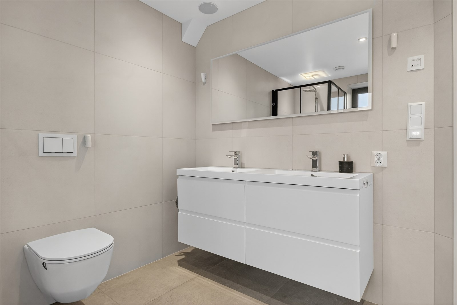 Flislagt baderom med fliser på både vegger og gulv, og en pen og moderne innredning. Galleribilde