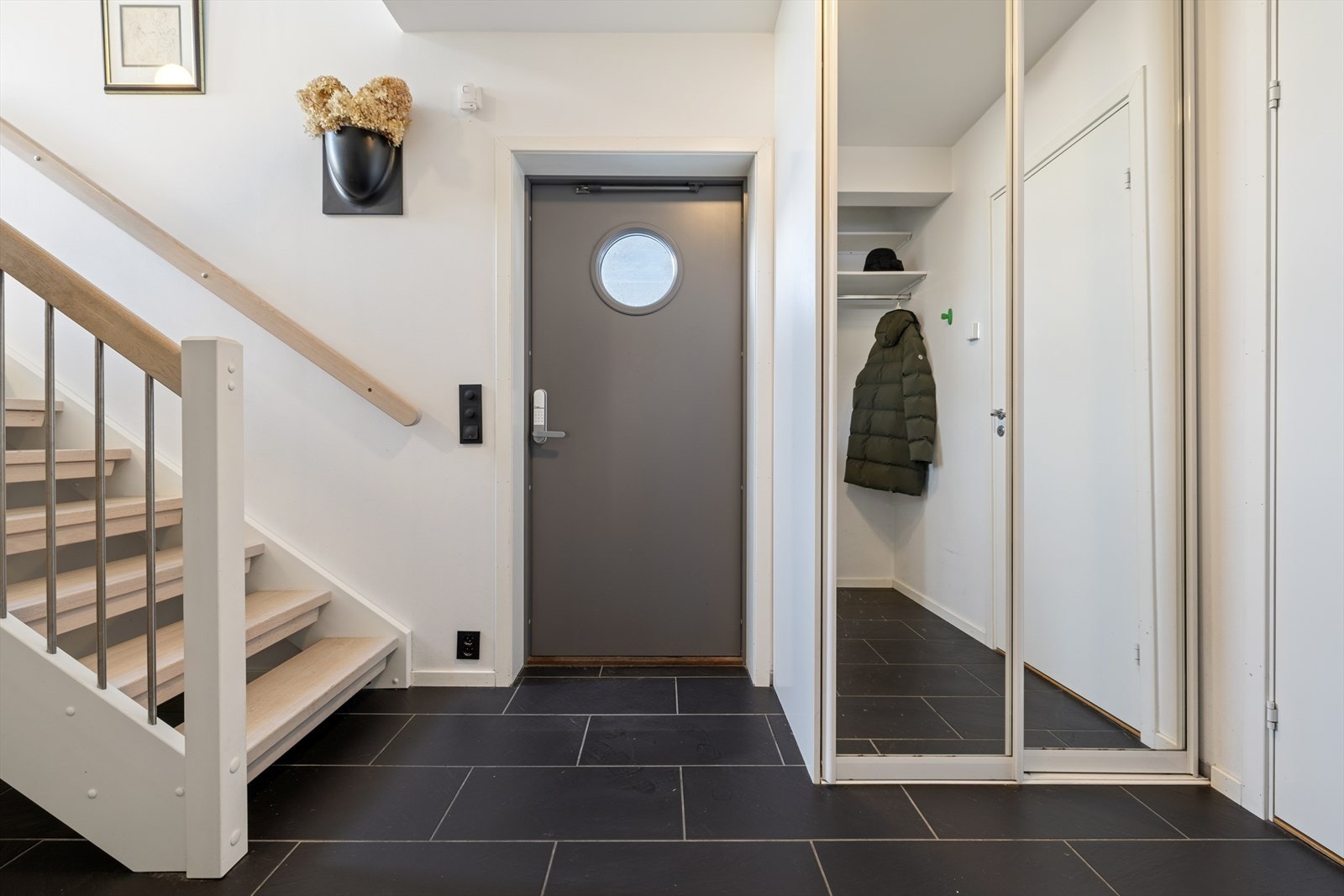 Inngangspartiet er romslig med praktiske fliser på gulvet. Den lakkerte tretrappen leder opp til andre etasje. Galleribilde