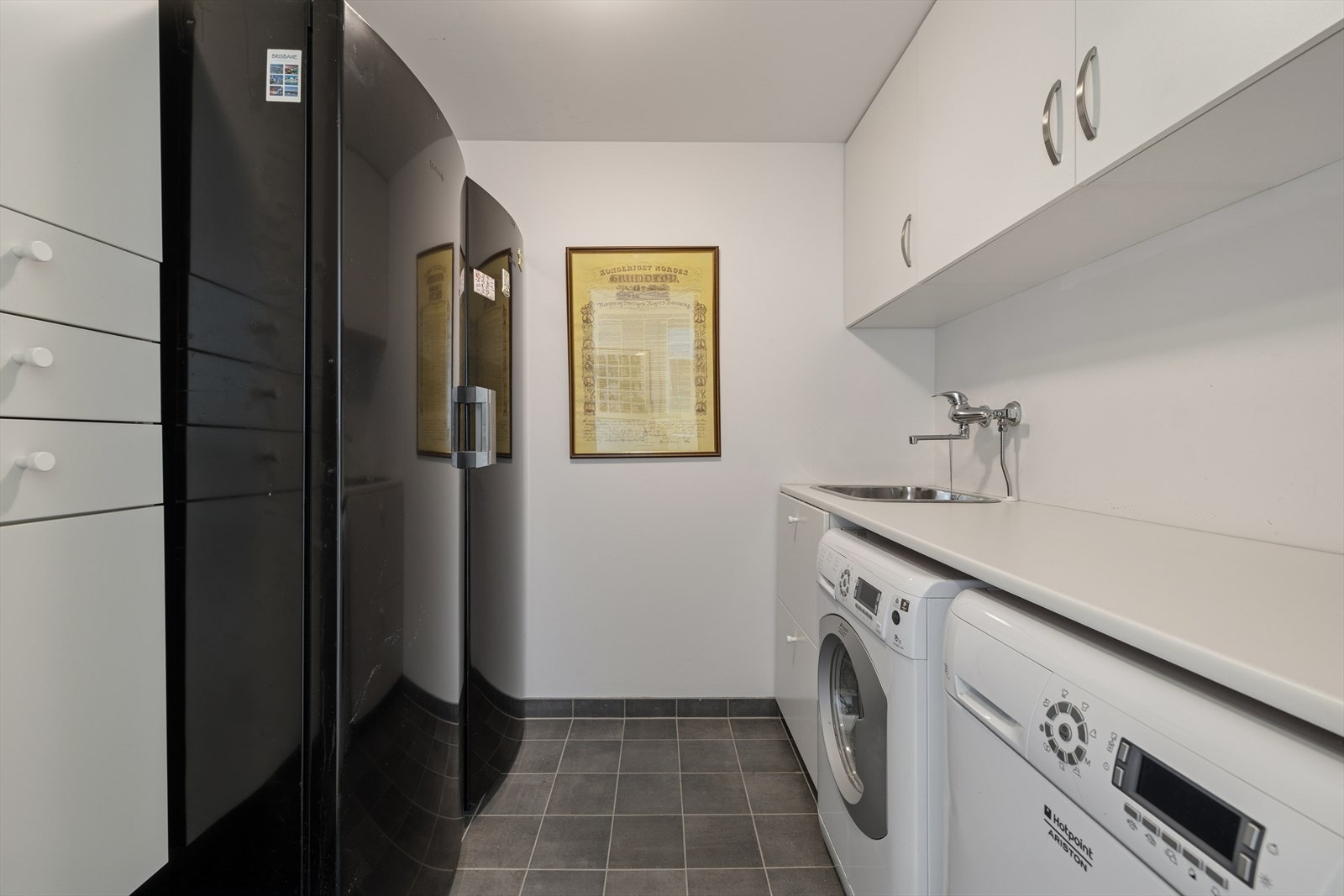 Separat vaskerom med flislagt gulv, opplegg for vaskemaskin og god oppbevaringsplass. Galleribilde