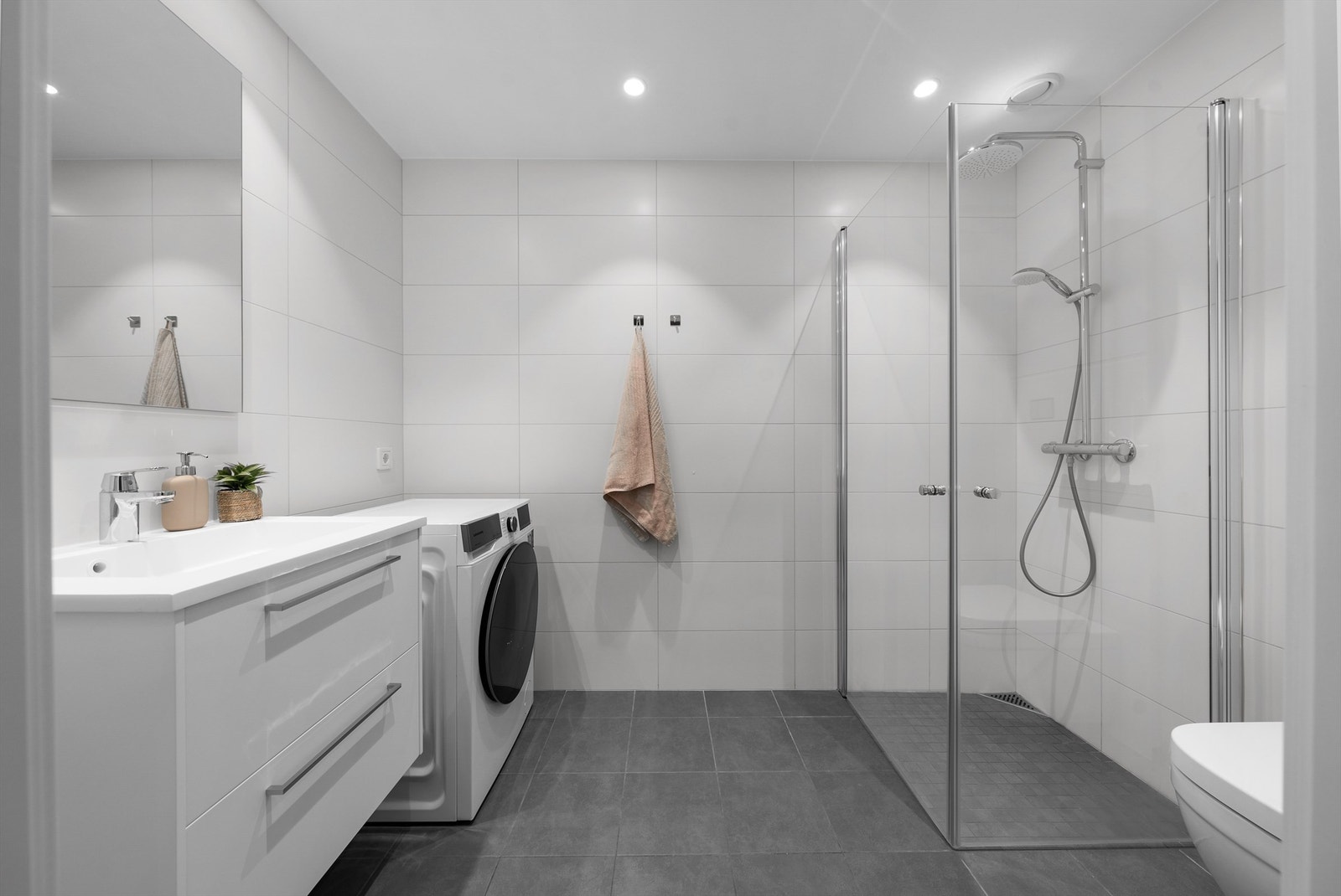 Moderne, flislagt bad fra byggeåret med elektriske varmekabler i gulv. Det er opplegg for vaskemaskin. Galleribilde