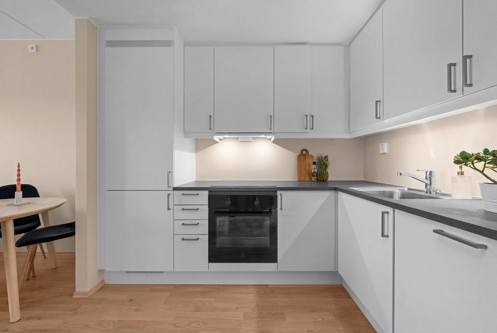 Kjøkkenet har en praktisk hjørneløsning med integrerte hvitevarer, inkludert induksjonstopp og stekeovn. Galleribilde