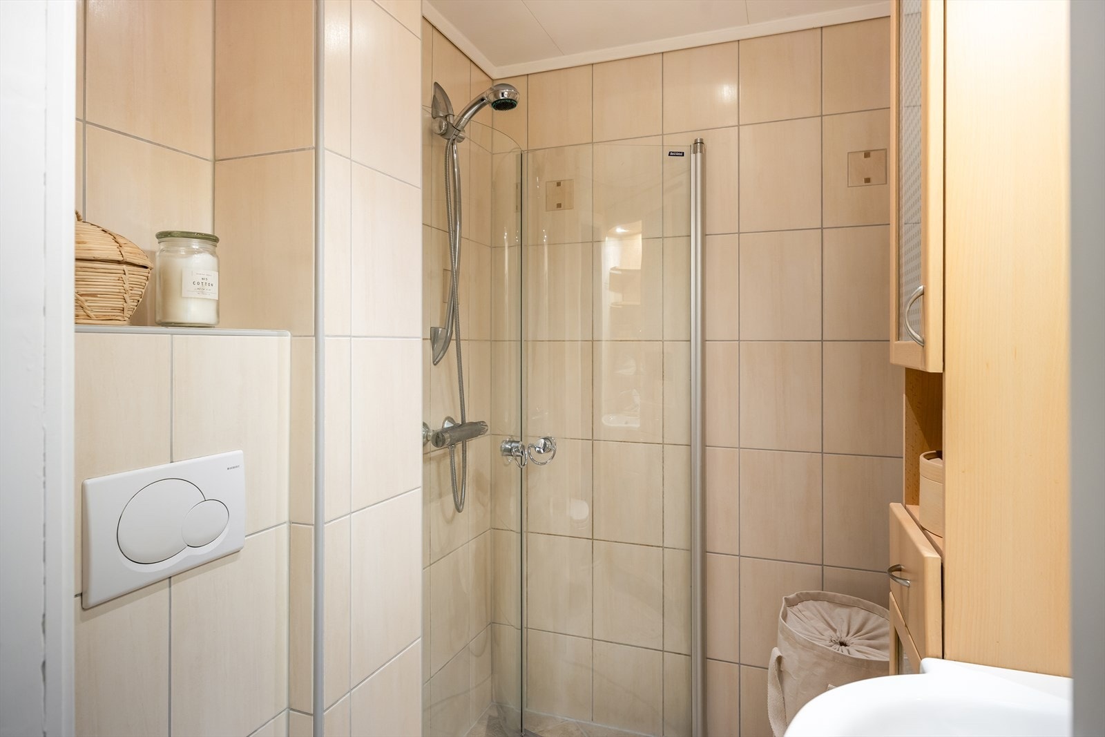 Badet er utstyrt med dusjvegger i glass, vegghengt toalett, innredning med servant og opplegg for vaskemaskin. Galleribilde