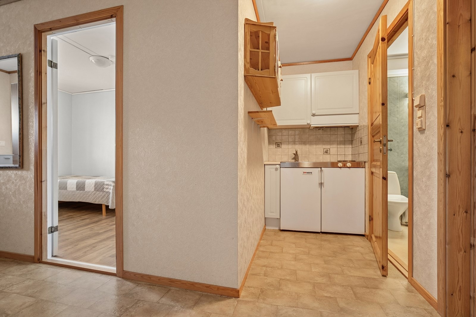 Hybelkjøkkenet har benkeplate med integrert koketopp, kjøkkenservant og kjøleskap Galleribilde