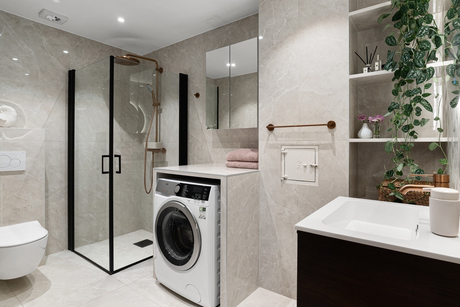 Rålekkert flislagt bad fra 2024 med fliser fra Modena, varmekabler, dusjnisje, veggmontert servant og toalett samt opplegg for vaskemaskin Galleribilde