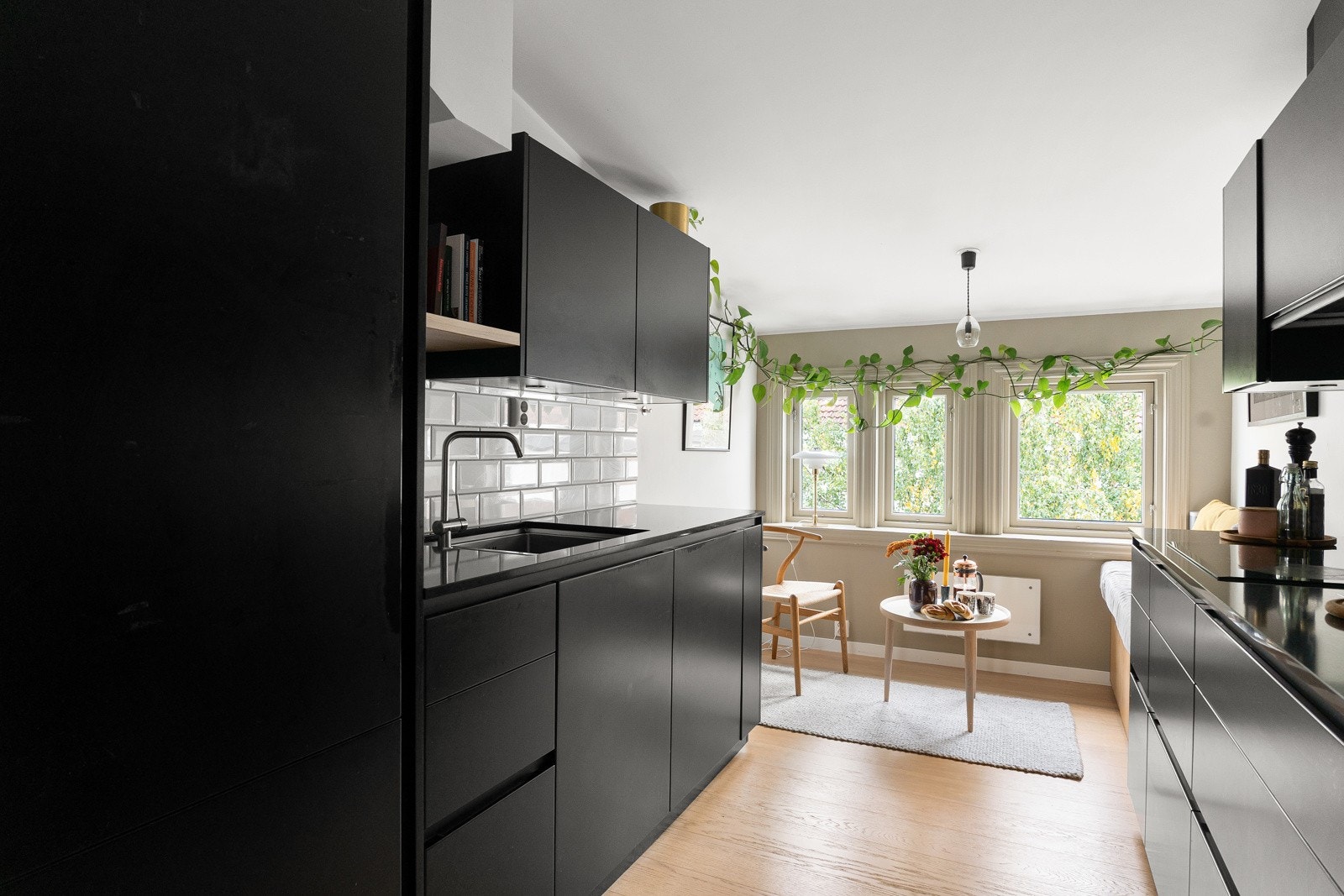 Kjøkkeninnredning med sorte grepsfrie fronter, overskap med benkebelysning og fliser på vegger samt sittebenk med oppbevaring Galleribilde