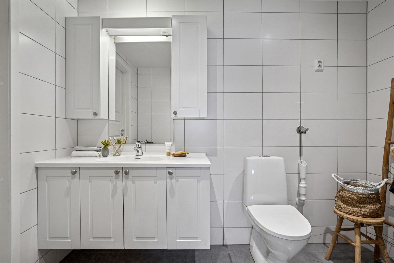 Badet inneholder en baderomsinnredning med nedfelt servant, toalett og et dusjhjørne med glassvegger. Det er også klargjort med opplegg for vaskemaskin. Galleribilde