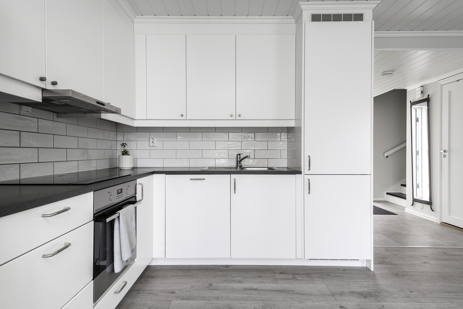 Hvite fronter og laminert benkeplate gir kjøkkenet et ryddig utseende. Galleribilde