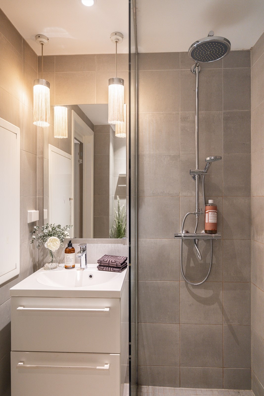 Badet fremstår moderne og delikat, med store fliser, stilfull dusjløsning og lys innredning Galleribilde