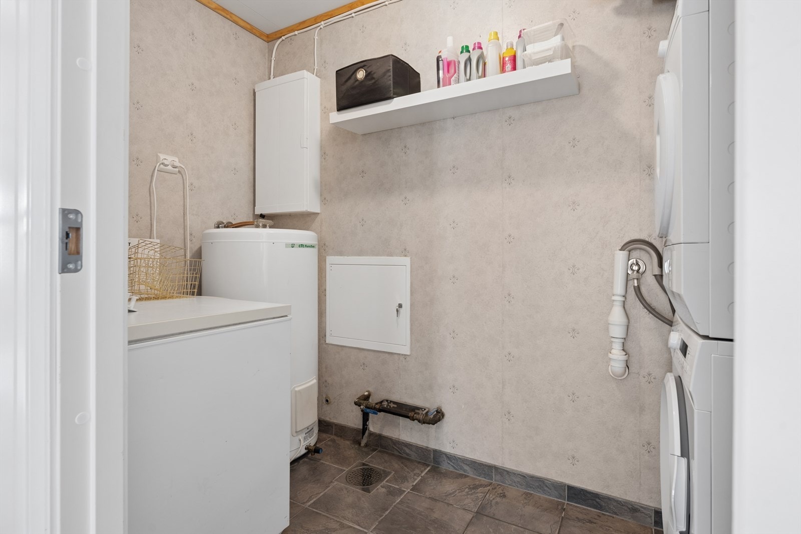 Vaskerommet er praktisk utformet med flislagt gulv, noe som gjør rommet lett å vedlikeholde. Her er det opplegg for vaskemaskin, samt plass til håndtering av klesvask og annen nødvendig oppbevaring. Et funksjonelt rom som bidrar til en praktisk hverdag Galleribilde