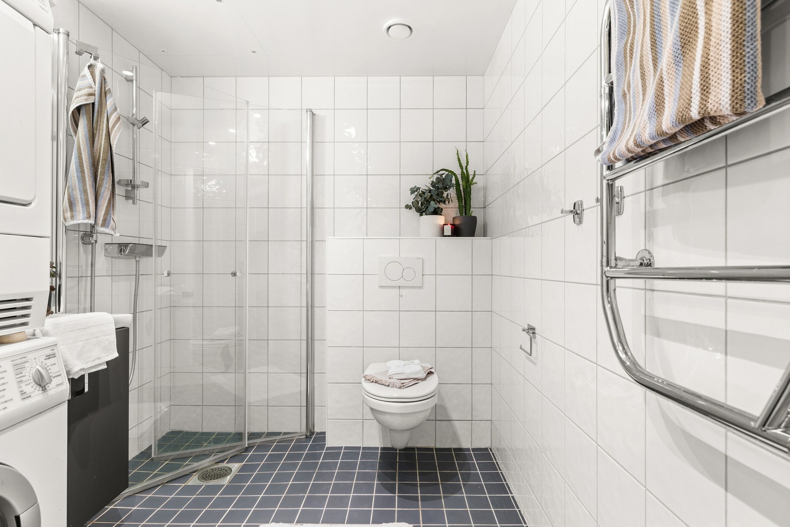 Romslig, flislagt baderom med varmekabler i gulv og downlights i himling Galleribilde